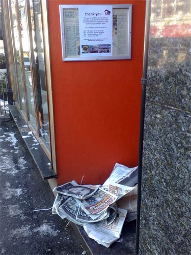 Newspapers piling up in the doorway